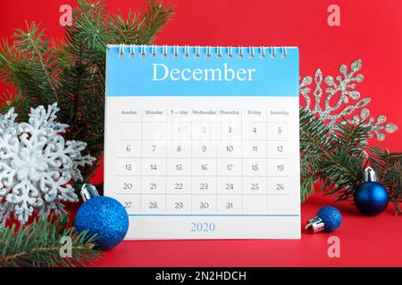 Flip-Kalender und Weihnachtsdekor auf rotem Hintergrund. Feiertagszähler Stockfoto