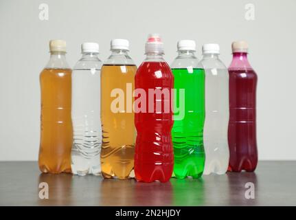 Flaschen mit alkoholfreien Getränken auf dem Tisch vor grauem Hintergrund Stockfoto