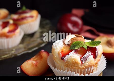 Leckere Cupcakes mit Pflaumen auf schwarzem Hintergrund, Nahaufnahme Stockfoto