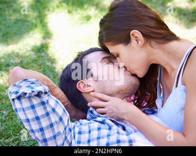 Verloren im Dunst der Frühlingsromantik. Ein junges Paar küsst sich im Park. Stockfoto