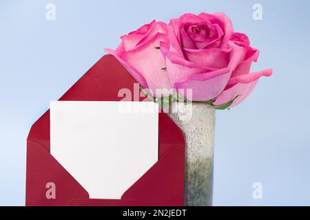 Roter Umschlag mit Papier für Text und Vase aus rosa Rosen auf blauem Hintergrund. Einladung, Geburtstag, 8. März, International Women's, Mother's da Stockfoto