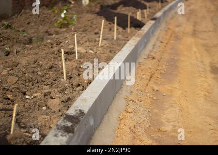 Neues Chaos auf der Straße. Reparatur von Straßen. Einzelheiten der Bauarbeiten. Betonblöcke sind im Boden fixiert. Baustellen im Hintergrund Stockfoto