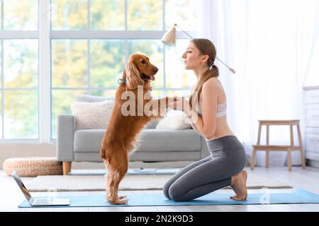 Sportliche junge Frau mit rotem Cockerspaniel zu Hause Stockfoto