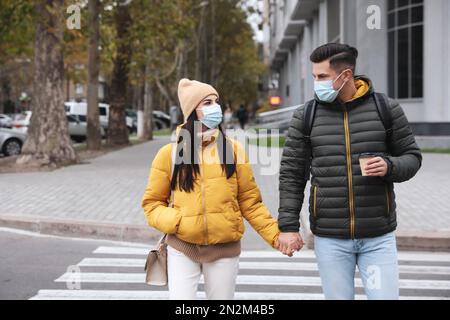 Ein Paar mit medizinischen Gesichtsmasken, das draußen läuft. Persönlicher Schutz während der COVID-19-Pandemie Stockfoto