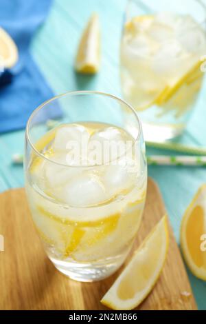 Sodawasser mit Zitronenscheiben und Eiswürfeln auf hellblauem Holztisch Stockfoto