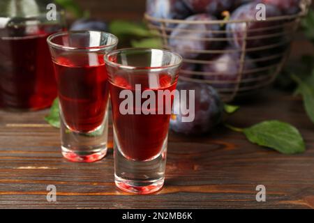 Köstlicher Pflaumenlikör auf einem Holztisch. Hausgemachtes, starkes alkoholisches Getränk Stockfoto