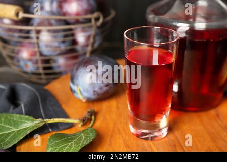 Köstlicher Pflaumenlikör in geschossenem Glas auf Holzbrett. Hausgemachtes, starkes alkoholisches Getränk Stockfoto