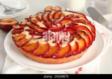 Köstlicher Kuchen mit Pflaumen auf einem hellen Tisch, Nahaufnahme Stockfoto