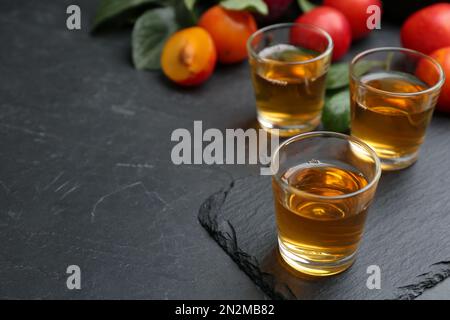 Köstlicher Pflaumenlikör auf schwarzem Tisch. Hausgemachtes, starkes alkoholisches Getränk Stockfoto