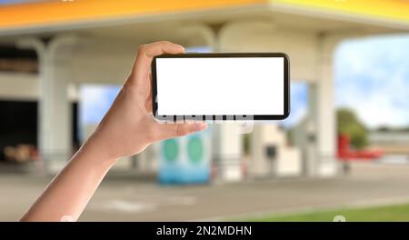 Frau, die für das Betanken per Smartphone an der Tankstelle bezahlt, Nahaufnahme. Gerät mit leerem Bildschirm Stockfoto
