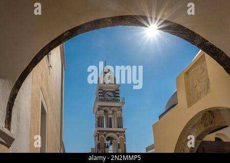 Glockenturm mit Uhr der katholischen Kathedrale Kirche Johannes des Täufers in Fira, durch den Bogengang gesehen, Insel Santorin, Kykladen, Stockfoto