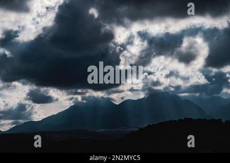 Dramatischer Himmel mit riesigen dunklen Wolken über zerklüfteten Bergsilhouetten in Spanien Stockfoto