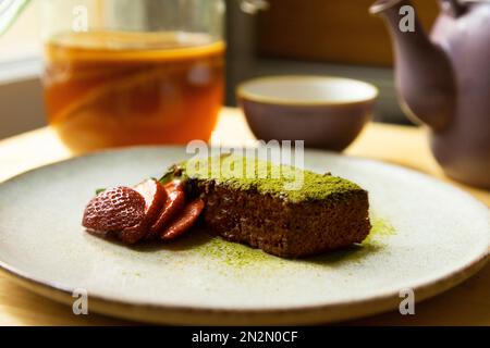 Eine Portion weicher Matcha-Schokoladenkuchen und Kombi-Tee. Stockfoto