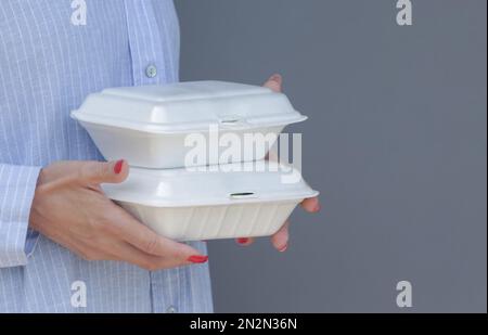 Frauenhände, die Lunchpakete aus Schaumstoff zum Mitnehmen halten. Einweg-Lebensmittelbehälter, Nahaufnahme. Stockfoto