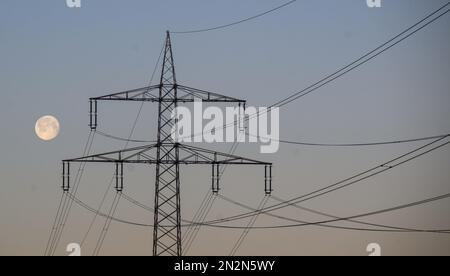 Hohenhameln, Deutschland. 07. Februar 2023. Der Mond ist am frühen Morgenhimmel hinter einer Hochspannungsleitung im Bezirk Peine. Kredit: Julian Stratenschulte/dpa/Alamy Live News Stockfoto