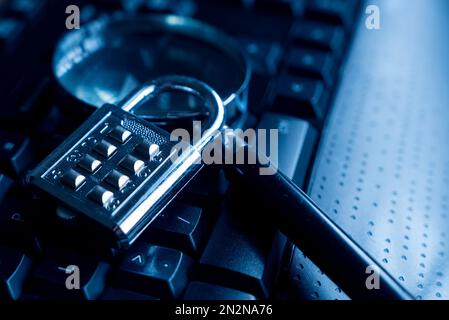 Computersicherheitskonzept. Ein Vorhängeschloss und eine Lupe auf einer Computertastatur. Stockfoto