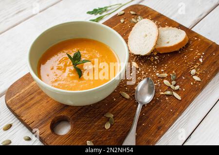 Leckere Kürbiscreme-Suppe mit Brot und Löffel Stockfoto