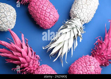 Pinkfarbene und weiße Ananas auf blauem Hintergrund, flach liegend. Kreatives Konzept Stockfoto