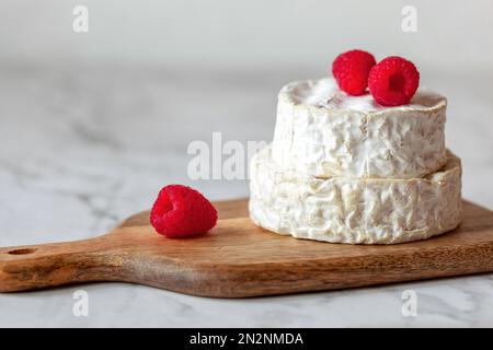 camembert französischer Weichkäse serviert mit Himbeeren, Minimalismus Stockfoto
