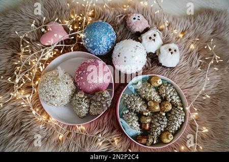 Wunderschöne Weihnachtsbaumkugeln, Spielzeuge und Lichterketten auf Kunstpelz, Blick über die Kulissen Stockfoto