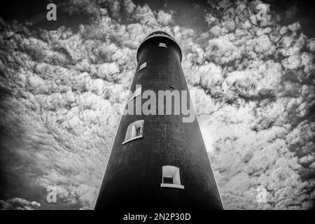 Der alte Leuchtturm von Dungeness in Kent, von unten gesehen, vor einem wirbelnden bewölkten Himmel Stockfoto