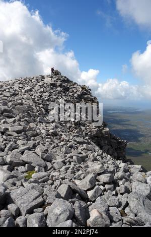Ein Mann, der auf Felsen und Felsen über den Schienenoberhängen auf dem Summit of the Corbett Cranstackie steht, North West Sutherland, Scottish Highlands, Großbritannien. Stockfoto