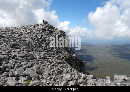 Ein Mann, der auf Felsen und Felsen über den Schienenoberhängen auf dem Summit of the Corbett Cranstackie steht, North West Sutherland, Scottish Highlands, Großbritannien. Stockfoto