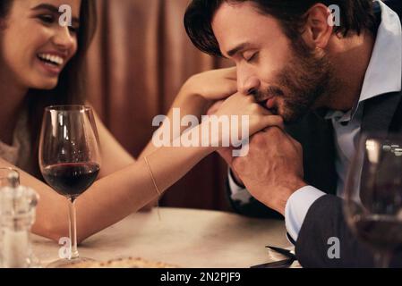 Hand, Kuss und Liebe mit einem Paar in einem Restaurant bei einem Date-Abend zusammen für feines Essen oder Luxus. Liebe, Romantik und Zuneigung zu einem Mann Stockfoto