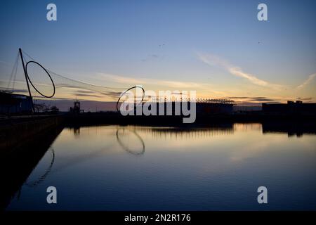 Middlesbrough, Großbritannien. 07. Februar 2023 Der klare Himmel und die niedrigen Temperaturen über Nacht führten zu einem wunderschönen Sonnenaufgang über dem Middlehaven Dock, der Temenos Kunstinstallation und dem Riverside Stadium des Middlesbrough Football Clubs, Teesside, Großbritannien. Kredit: Teesside Snapper/Alamy Live News. Stockfoto