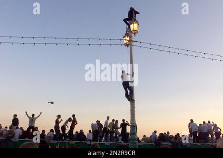 Diese Partygänger kletterten einen Lampost, um einen Aussichtspunkt für die Fatboy Slim Big Beach Boutique Party zu bekommen, wo für den Abend schätzungsweise 200000 Leute an die Brighton Seafront kamen. Norman Cook , der Tanzmusiker und DJ , organisierte und bezahlte die Veranstaltung für das zweite Jahr . Foto von Simon Dack, Juli 2002 Stockfoto