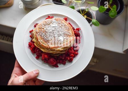 Ein Stapel amerikanische Pfannkuchen mit Himbeeren und Puderzucker. Stockfoto