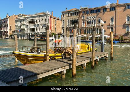 Ein DHL-Kurierboot, das zum Entladen von Kisten auf dem Canale Grande angelegt hat, mit Palästen Cà Sagredo und Cà d'Oro im Hintergrund, Venedig, Venetien, Italien Stockfoto