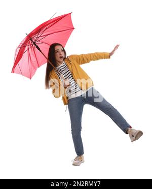 Emotionale Frau mit Regenschirm, die in Windböen auf weißem Hintergrund gefangen war Stockfoto