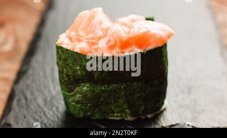 Leckeres frisches Sushi-Maki auf schwarzem Schiefer Stockfoto
