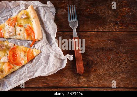 Zwei Scheiben Pizza auf einem Holztisch, flach liegend Stockfoto