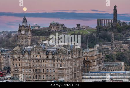 Blick auf den Uhrenturm des Balmoral Hotels und Calton Hill mit Vollmond in der Dämmerung, Edinburgh, Schottland, Großbritannien Stockfoto
