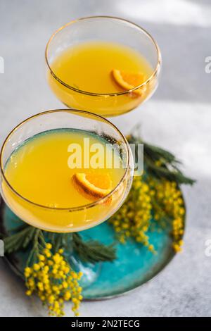 Nahaufnahme von zwei Champagner-Mimosa-Cocktails mit gelben Mimosa-Blumen Stockfoto