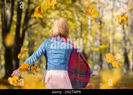 Ein rothaariges Mädchen geht durch den Herbstpark. Stockfoto