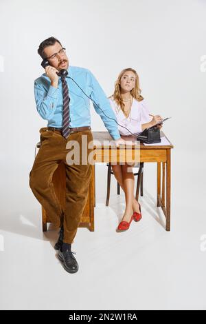 Geschäftsmann telefoniert und Frau, persönliche Assistentin macht Notizen vor grauem Hintergrund. Geschäftskonzept, Beschäftigung, Arbeit Stockfoto