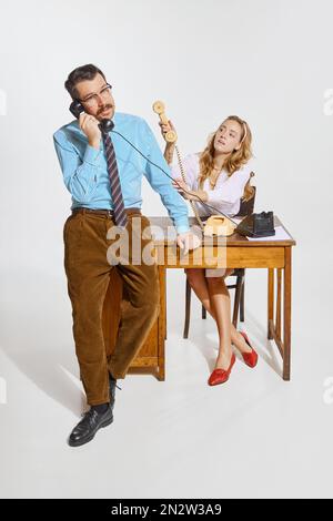 Geschäftsmann telefoniert und Frau, persönliche Assistentin macht Notizen vor grauem Hintergrund. Geschäftskonzept, Beschäftigung, Arbeit Stockfoto