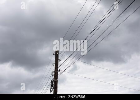 Kabel gegen den Himmel. Stange mit Drähten. Elektrische Ausrüstung. Stromleitungen. Stockfoto