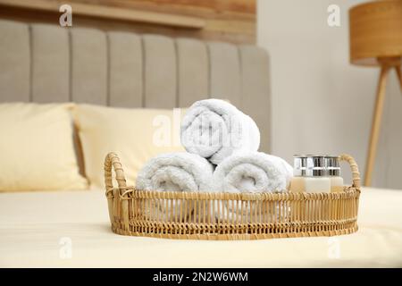 Gerollte saubere Handtücher und Shampooflaschen auf dem Bett im Haus Stockfoto