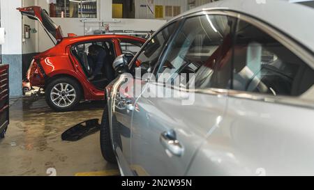 Autos in einem Autohändler, Seitenansicht eines silbernen Autos und eines roten Autos davor. Hochwertiges Foto Stockfoto