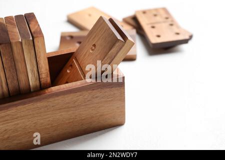 Set aus hölzernen Dominosteinen in einer Box auf einem weißen Tisch, Nahaufnahme Stockfoto