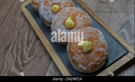 Hausgemachte gebratene Donuts gefüllt mit Vanille und gewürzt mit einem Schleier Zucker Stockfoto