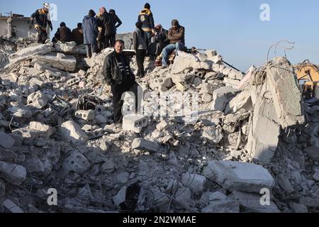 Harem, Syrien. 07. Februar 2023. Zivilisten und Mitglieder des Weißhelms inspizieren ein Gebäude, das in der Stadt Harem nach dem verheerenden Erdbeben, das die türkisch-syrische Grenze traf, einstürzte und mehr als 5000 Menschen tötete. Kredit: Anas Alkharboutli/dpa/Alamy Live News Stockfoto