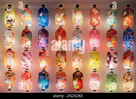 Verschiedene Arten von bunten japanischen Laternen, die an der Wand hängen. Stockfoto