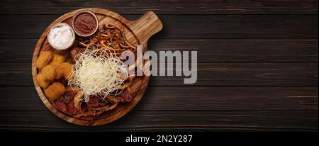 Biersnacks mit verschiedenen Saucen. Tintenfisch, basturma, Nuggets, auf einem Holzbrett, auf einem hölzernen Hintergrund. Banner Stockfoto