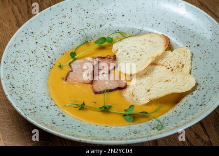 Gerichte vom Küchenchef des Restaurants. Ein Gericht auf einem Tisch in einem Café. Leckeres Essen von der Speisekarte des Restaurants. Frisches und leckeres Essen. Kürbissuppe Spri Stockfoto