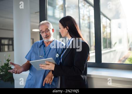 Junge Geschäftsfrau, die mit dem älteren Arzt Hand schüttelt. Stockfoto